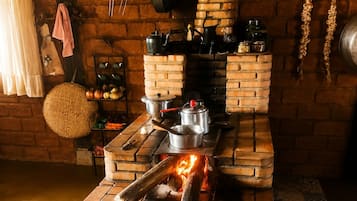 Cozinha com fogão de tijolos, utensílios de cozinha e um suporte para panelas suspenso.