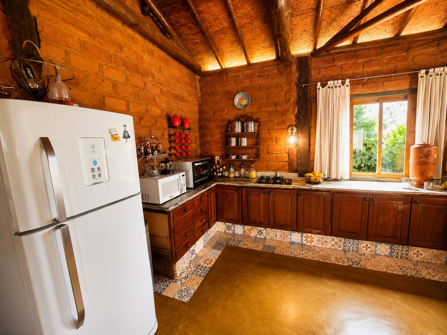Una cocina con refrigerador, microondas y gabinetes de madera.
