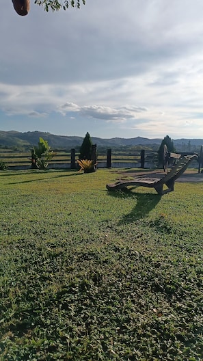 A grassy field with a wooden bench and a fence.
