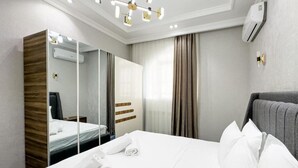 Una habitación de hotel con una cama grande, un espejo, un armario y una lámpara en el techo.