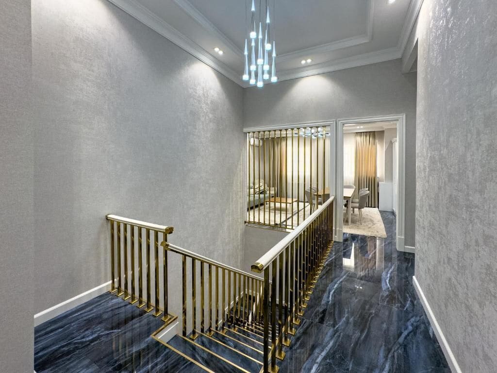 A staircase with marble steps and gold railings, leading to a room with a view.