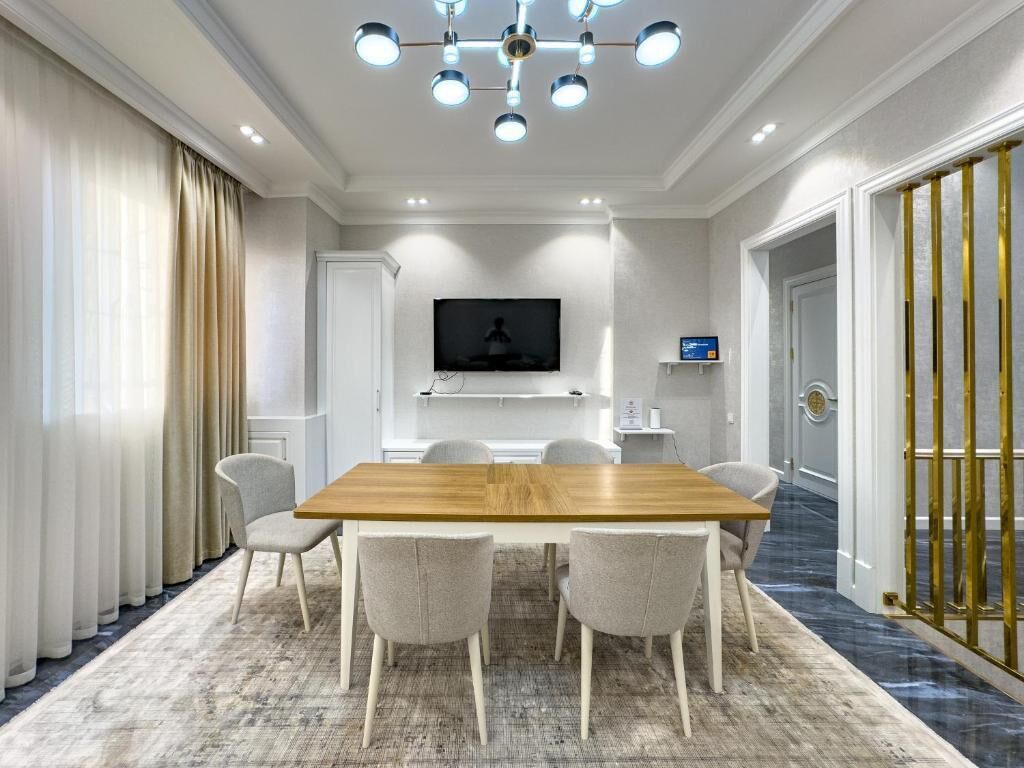 Una sala conferenze con un tavolo in legno, sei sedie, un televisore a schermo piatto e una porta con cornice dorata.