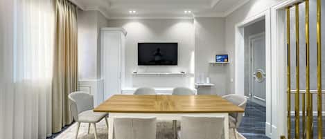 Un salón de conferencias con una mesa de madera, seis sillas, un televisor de pantalla plana y una moderna lámpara de araña.
