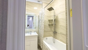 Un baño con bañera, ducha y espejo.