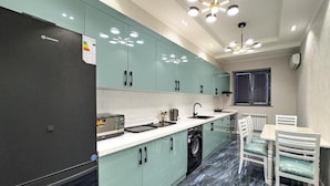 Una cocina moderna con lavadora integrada, un comedor con mesa y sillas, y una lámpara en el techo.