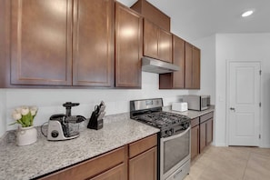A kitchen with wooden cabinets, a stainless steel stove, a microwave, and a toaster.