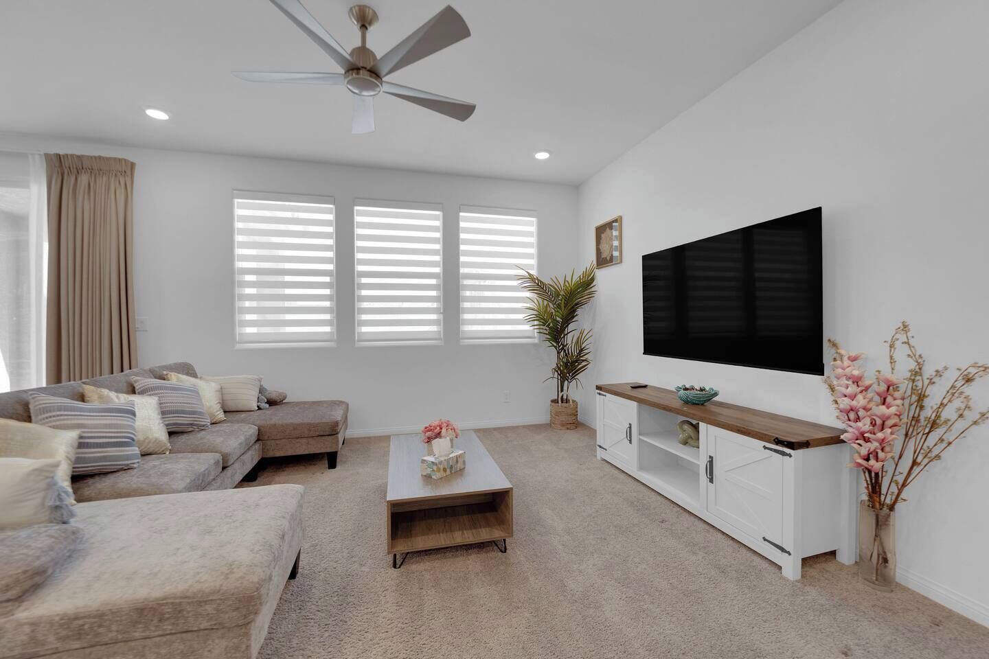 Una sala de estar moderna con un conjunto de sofá, una mesa de centro, un televisor y un ventilador de techo.