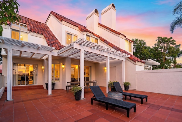 A house with a covered patio, outdoor furniture, and a view of the sunset. - Pergola Terrace + Fireplace + Pool + Gym | Salt Creek + Harbor | Terracotta (Dana Point)