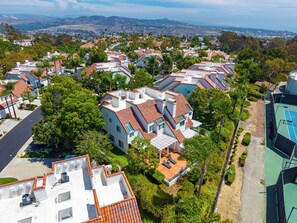 A residential area with multiple houses, some with red-tiled roofs, surrounded by greenery and trees. - Pergola Terrace + Fireplace + Pool + Gym | Salt Creek + Harbor | Terracotta (Dana Point)