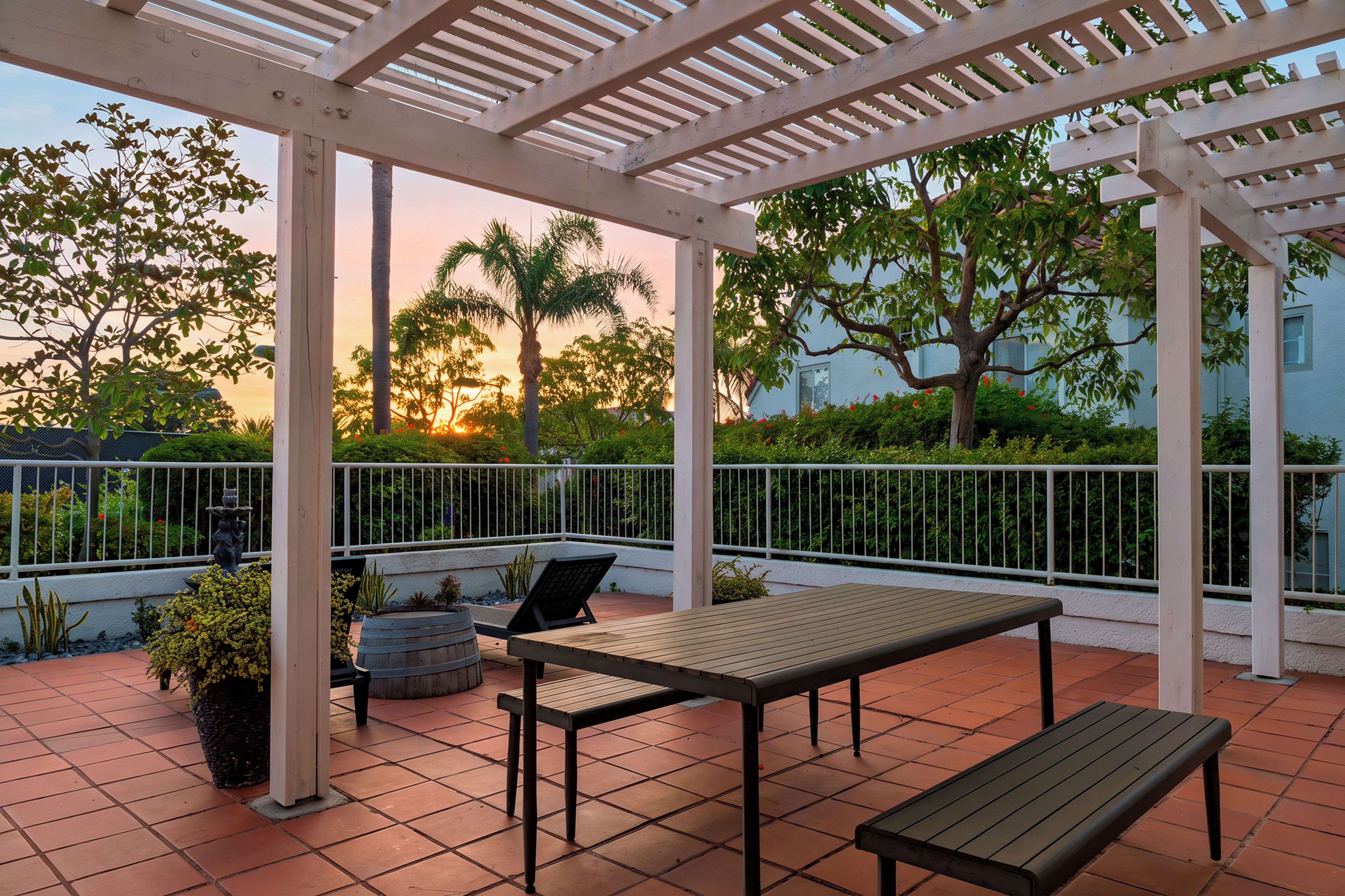 An outdoor patio with a pergola, seating, and potted plants.