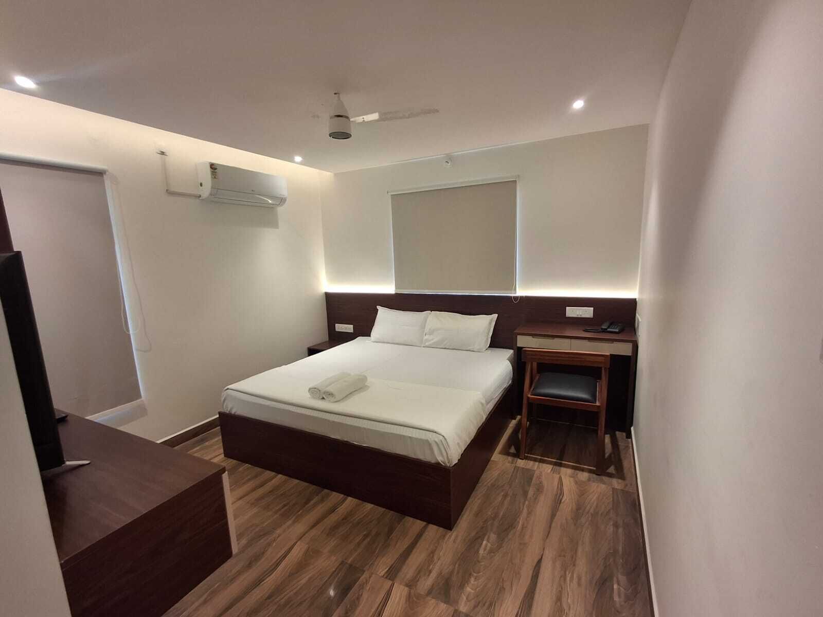Una habitación de hotel con cama, mesita de noche y escritorio.