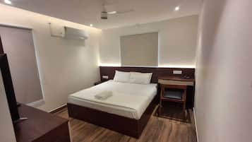 Una habitación de hotel con cama, mesita de noche y escritorio.