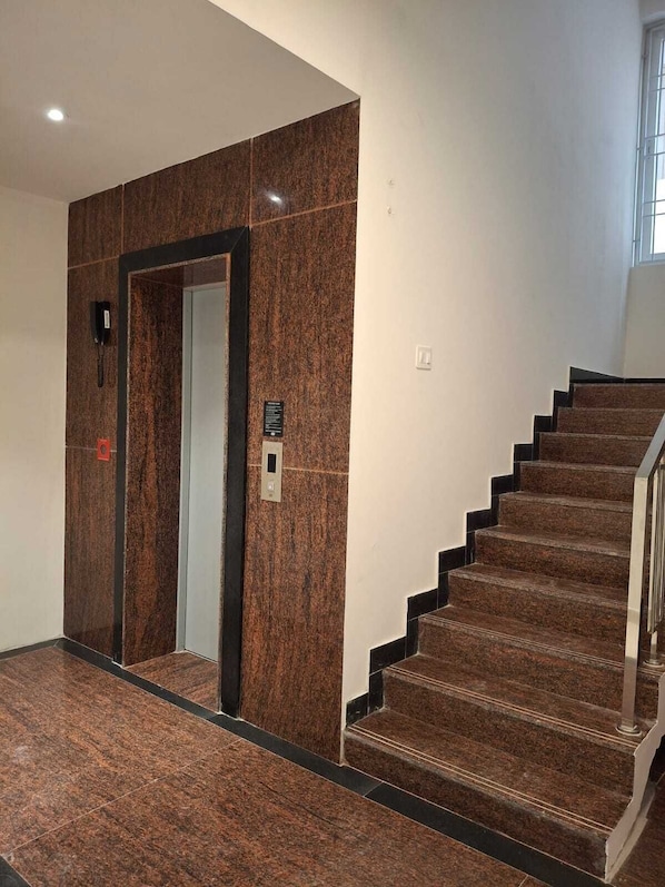 A staircase with a handrail and a wall with a door.