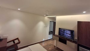Una sala de estar moderna con televisor de pantalla plana, muebles de madera e iluminación empotrada en el techo.