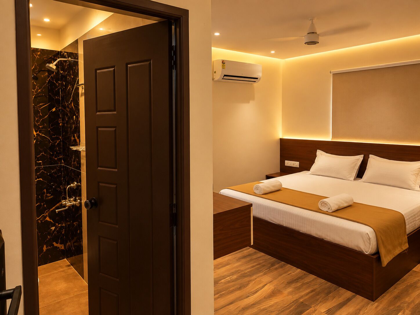 Habitación de hotel con cama, mesita de noche, equipo de aire acondicionado y zona de ducha con paredes de mármol.
