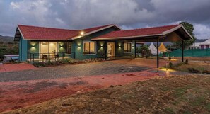 A two-story building with a red-tiled roof, a covered patio area, and a landscaped garden.