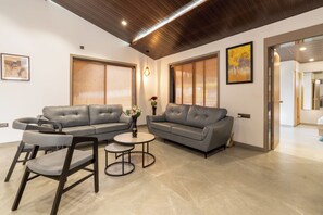 A modern living room with two grey sofas, a round coffee table, and a small side table.