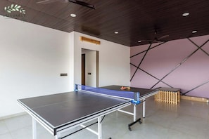 A ping pong table in a room with a sloped ceiling and a door leading to another area.