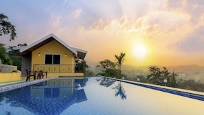 Vue sur un bâtiment jaune depuis la piscine, avec un ciel dégagé et un coucher de soleil.