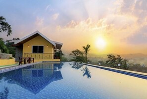 A poolside view of a yellow building with a clear sky and sunset.