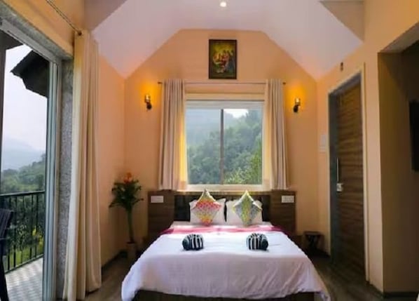 A bedroom with a bed, a window, a balcony, and a painting on the wall.