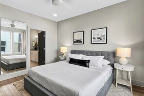 A modern bedroom with a large bed, bedside lamps, and two framed pictures on the wall. - Open-Concept Design + Game Stash | Mins to Five Points | Harmony House (Nashville)