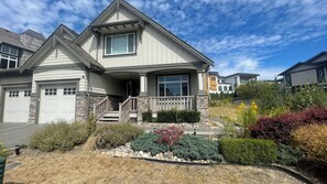 A two-story house with a stone facade, a front porch, and a driveway.