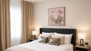 Une chambre d’hôtel avec un grand lit, deux tables de chevet avec des lampes, un élément décoratif mural et une fenêtre avec des rideaux.