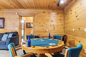 Ein Holzinterieur mit einem runden Spieltisch, umgeben von Stühlen, und einer Couch im Hintergrund.