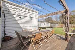 Eine Holzterrasse mit Tisch und Stühlen, einem Hängesessel und einem kleinen Fahrzeug.