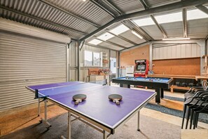 Ein Innenbereich mit Erholungsbereich, der einen Tischtennis-, Billardtisch und ein Arcade-Spielgerät umfasst.