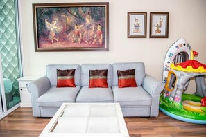A living room with a grey sofa, a glass coffee table, and a colorful inflatable play structure. - E609 Spacious 3-bedroom apartment in terrific with Playground near Beach (Nongkae)