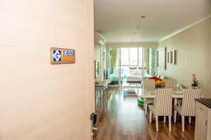 A hotel room with a wooden floor, a dining area with striped chairs, a bed with a white headboard, and a large window. - E609 Spacious 3-bedroom apartment in terrific with Playground near Beach (Nongkae)