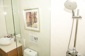 Et badeværelse med vask, toilet og bruser.