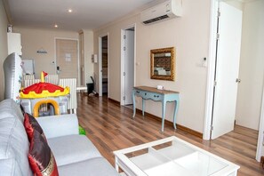 A living room with a sofa, a small table, and a play tent. There is a door leading to another room and an air conditioning unit on the wall. - E609 Spacious 3-bedroom apartment in terrific with Playground near Beach (Nongkae)