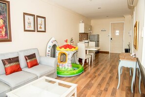 Een woonkamer met een bank, een salontafel, een eettafel met stoelen en een keuken op de achtergrond.