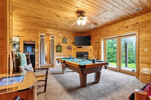 A wooden interior with a pool table, a television, and a fireplace. - Hot Tub + Arcade + Billiards | Mountain Views + Outdoor Dining | Bear Paw Cabin (Gatlinburg)