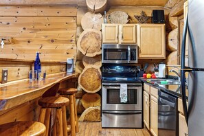 Eine Küche mit Holzwänden, einer Bar und Edelstahlgeräten, darunter eine Mikrowelle, ein Backofen und ein Kühlschrank.