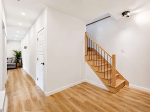A modern interior with a wooden staircase, white walls, and a wooden floor. - Hot Tub | Forest | 10 Guests | Whiskey Mountain (Nominingue)