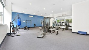 A gym with various exercise equipment, a punching bag, and a bench. - Mascot Luxe 2BR | Airport | Pool + 2 Parking (Mascot)