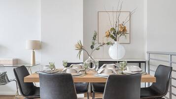 Comedor con mesa de madera dispuesta para cuatro, rodeada de sillas negras con detalles dorados.