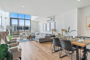 Una sala de estar moderna con comedor, ventanas amplias y vista del edificio exterior.