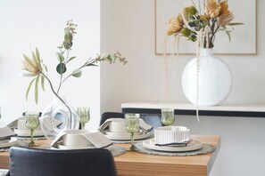 Una mesa de comedor con platos, vasos y un florero con flores secas.