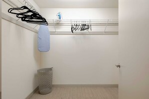 A laundry area with hanging clothes, a drying rack, a blue towel, and a trash bin. - Dallas Suite I Luxury High Rise (Dallas)