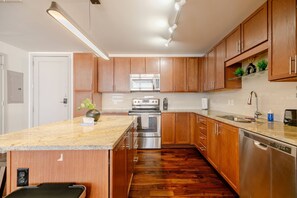 A modern kitchen with wooden cabinets, stainless steel appliances, and a granite countertop. - Dallas Suite I Luxury High Rise (Dallas)