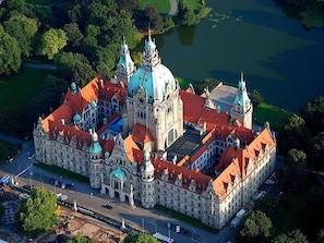 Ein großes, historisches Gebäude mit mehreren Türmen und Kuppeln, umgeben von Wasser und Grünflächen.