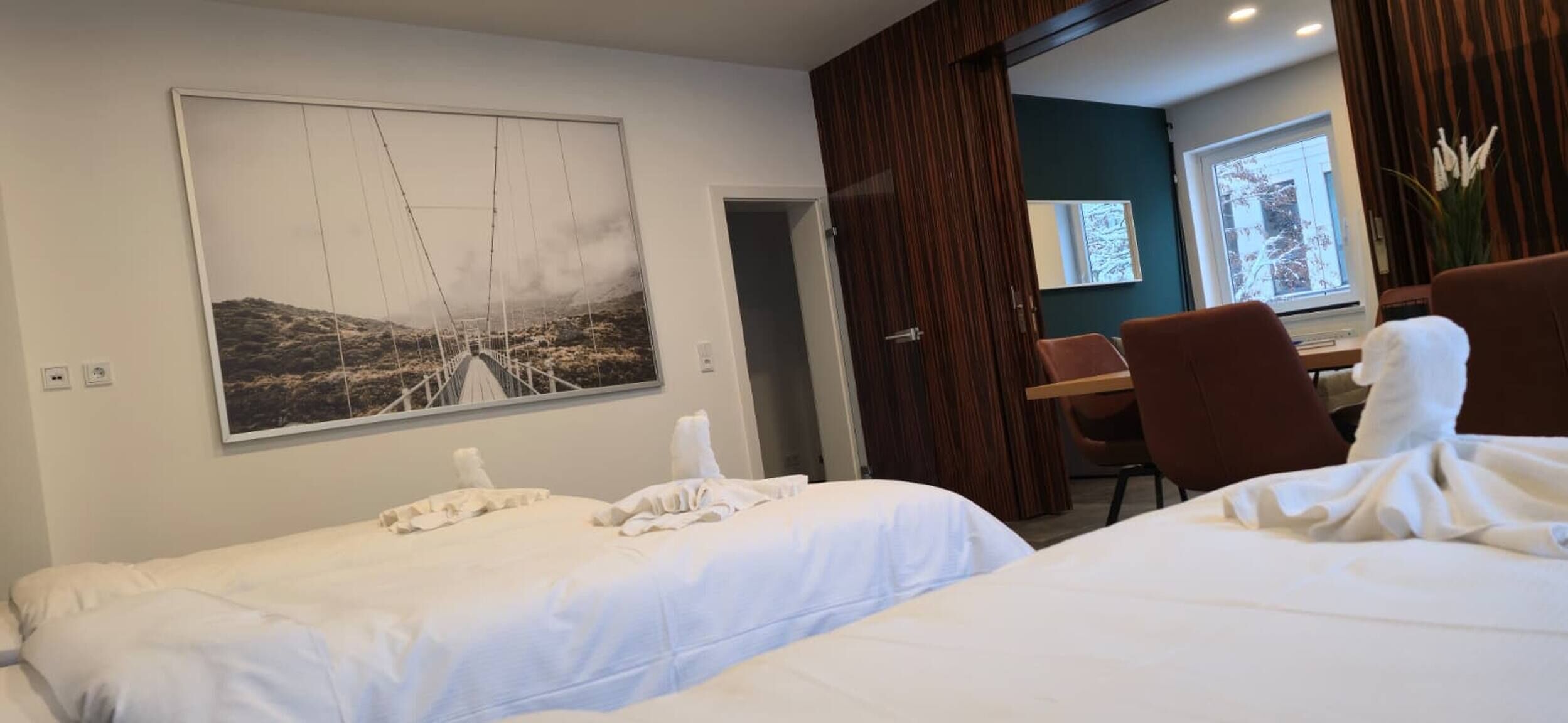Una camera d'albergo con due letti, una scrivania e una sedia.