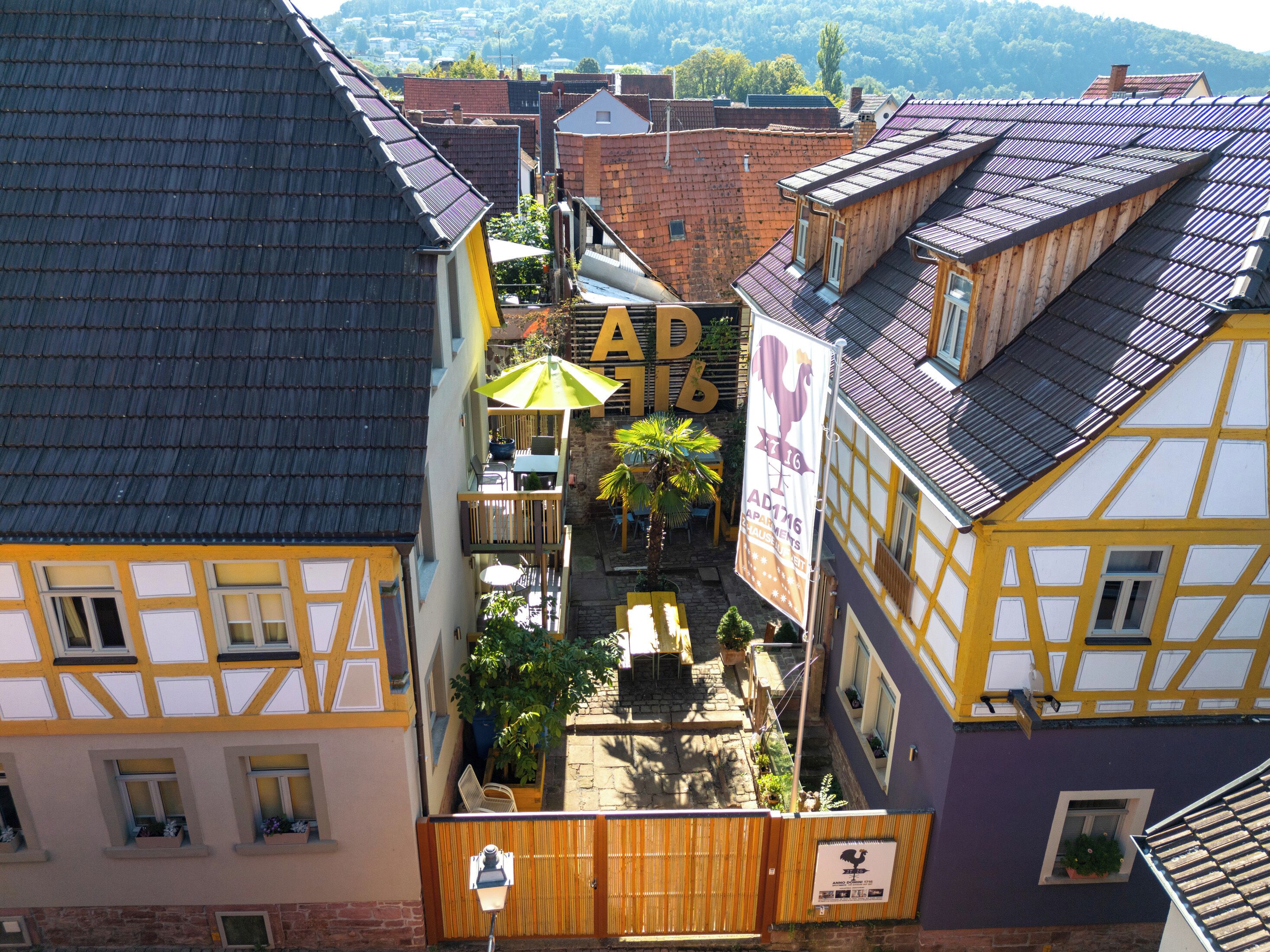 A courtyard with a wooden fence, a yellow umbrella, and a sign with the number 16.