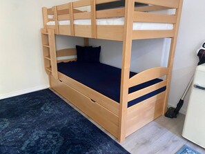A bunk bed with a ladder, a drawer, and a vacuum cleaner in the room. - Mutterstadt Oasis Two Apartment (Mutterstadt)