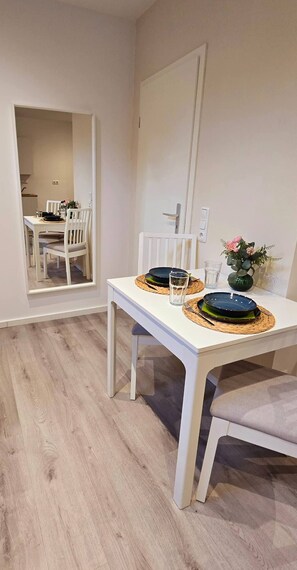 A dining area with a white table, two chairs, and a vase with flowers. - Mutterstadt Oasis Two Apartment (Mutterstadt)